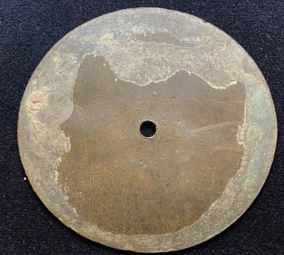 A brass artifact of circular shape with a small central hole